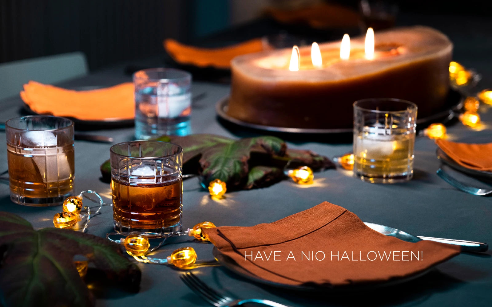 tavola con candele e bicchieri cocktail con ghiaccio con scritta have a NIO halloween